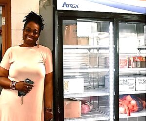 Smiling woman standing by a full community fridge